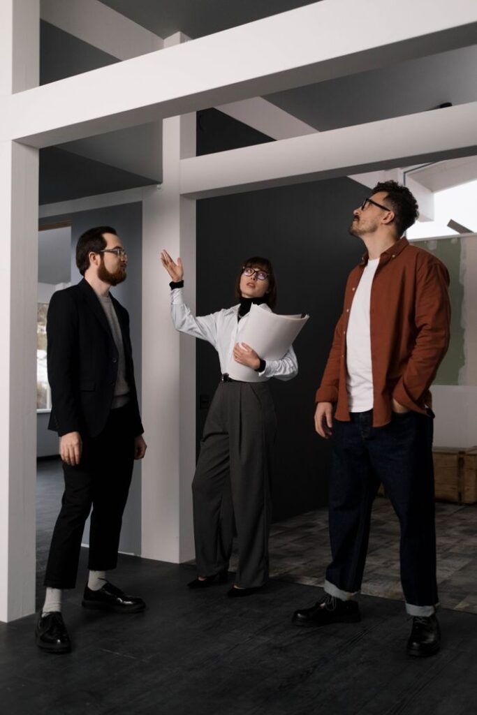 Three adults in a modern office engaged in a professional discussion.